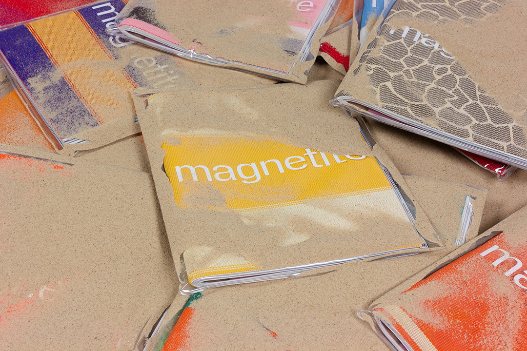 Luxury printed magazines partially covered in sand with unique covers made from recycled beach chair materials, sustainable print London