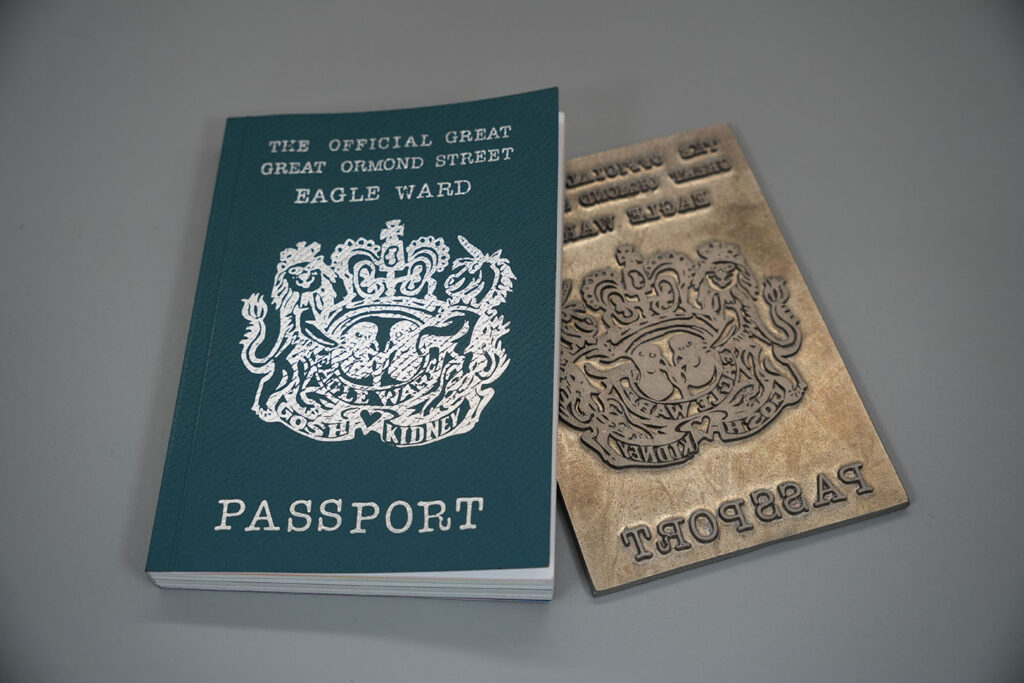 Premium booklet with silver foil blocked cover alongside a custom printing die, showcasing luxury print finishing, foil stamping and bespoke publication production