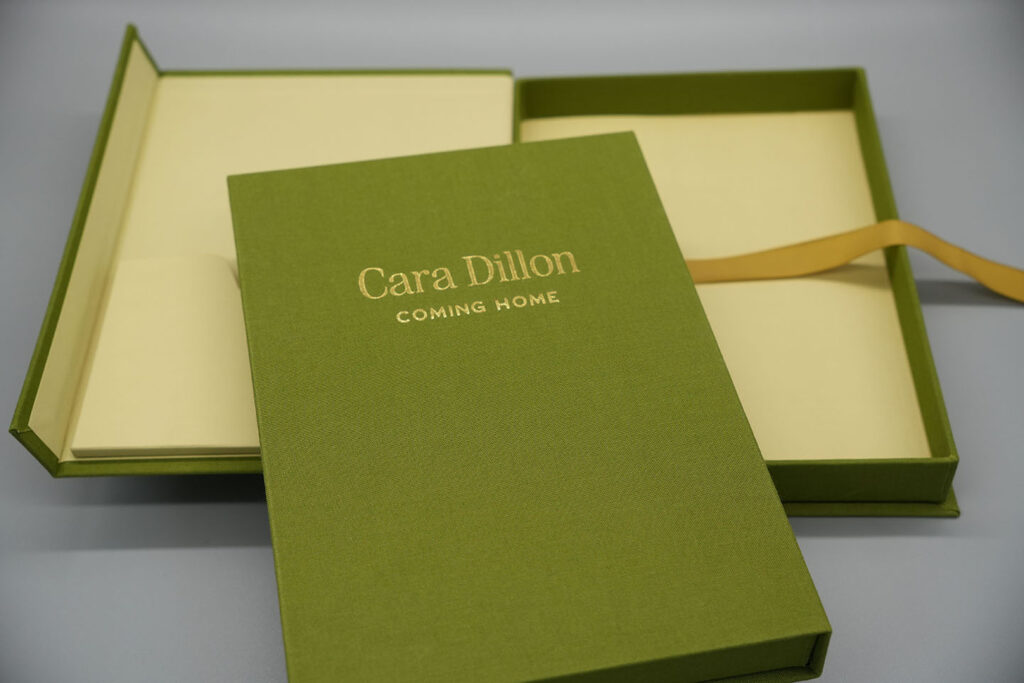 Luxury green cloth-bound rigid presentation box with gold foil branding and ribbon pull, showcasing bespoke packaging and premium print finishing