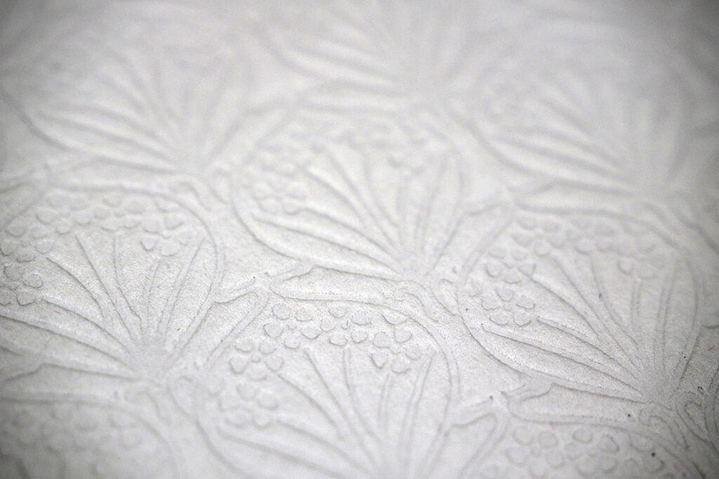 Close-up of luxury debossed floral artwork on premium uncoated paper, showcasing tactile print finishing and high-end bespoke print craftsmanship