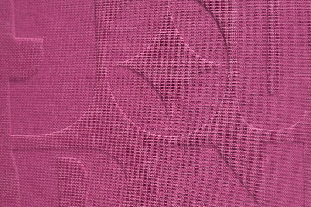Detailed view of debossed letterforms on premium textured paper with a tactile finish