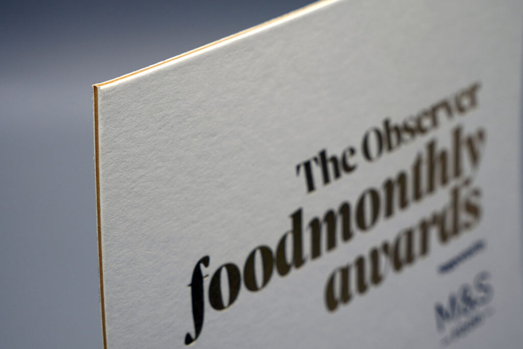 Close-up of premium duplex/triplex board with a textured surface, layered edge, and high-quality printed typography